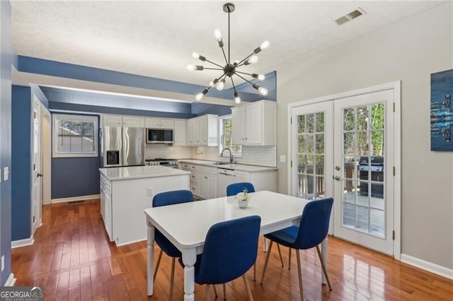 dining room featuring visible vents, baseboards, a chandelier, french doors, and hardwood / wood-style flooring