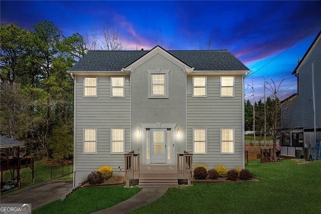 colonial house with a yard and roof with shingles