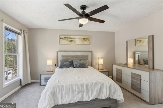 bedroom featuring a ceiling fan, light colored carpet, baseboards, and a textured ceiling