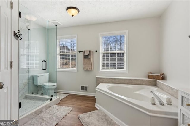 full bathroom with wood finished floors, baseboards, visible vents, a stall shower, and a garden tub