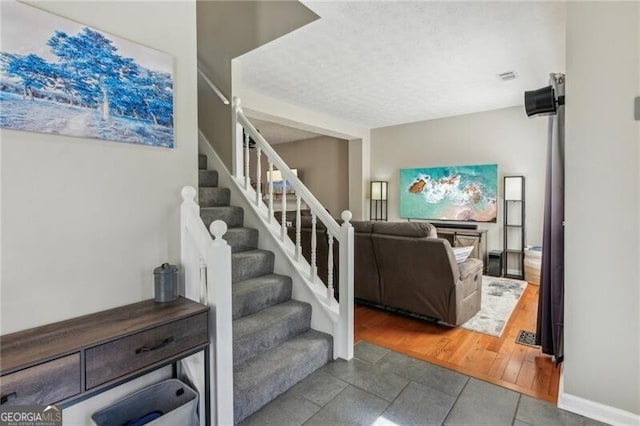 staircase featuring tile patterned floors, baseboards, and a textured ceiling