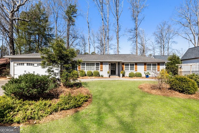 ranch-style home with a garage, board and batten siding, and a front lawn