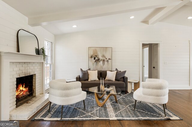 living area with wood walls, a brick fireplace, lofted ceiling with beams, and wood finished floors