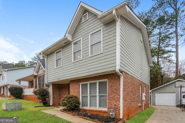 view of front of house featuring brick siding, a detached garage, an outbuilding, and a front yard