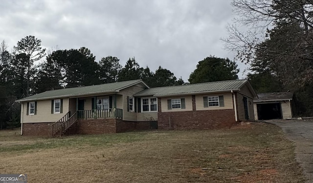 ranch-style house with a front yard, driveway, covered porch, a garage, and metal roof