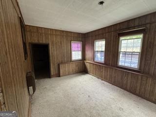 empty room with light colored carpet and wood walls