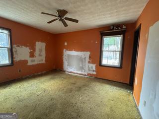 unfurnished living room featuring plenty of natural light and a ceiling fan