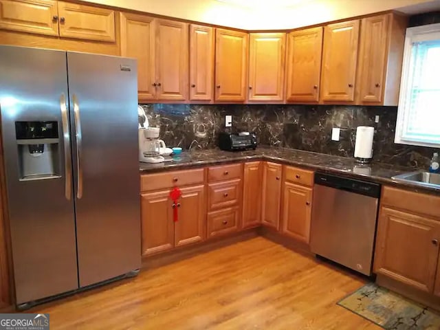 kitchen featuring decorative backsplash, a sink, light wood-style floors, and stainless steel appliances