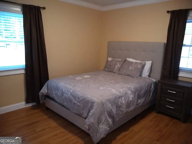 bedroom featuring baseboards, wood finished floors, and ornamental molding