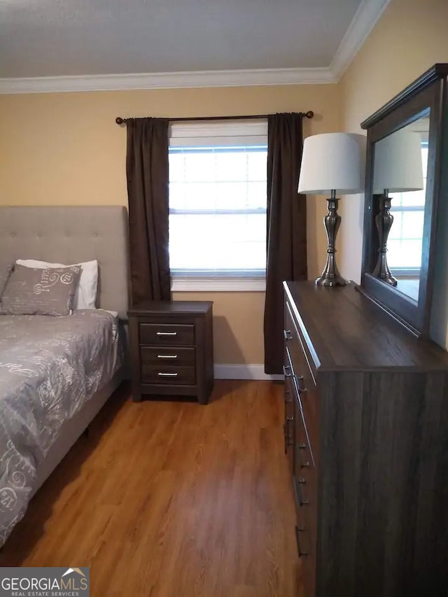 bedroom featuring light wood finished floors, crown molding, and baseboards