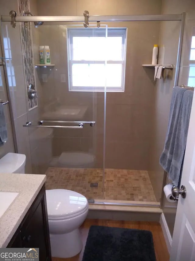 full bath with vanity, a shower stall, and toilet