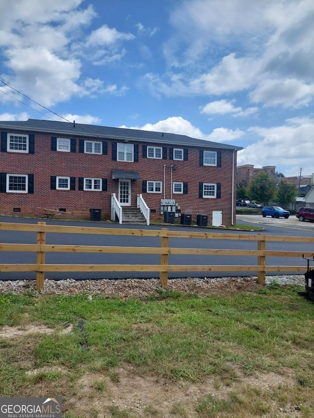 view of property with entry steps, fence, and central AC