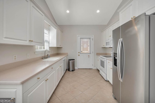 kitchen with lofted ceiling, light tile patterned floors, white appliances, white cabinetry, and a sink