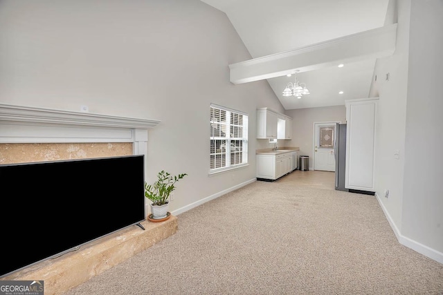 unfurnished living room with light carpet, high vaulted ceiling, baseboards, and an inviting chandelier