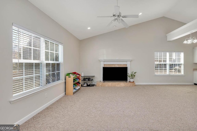 playroom with baseboards, carpet floors, a fireplace with raised hearth, vaulted ceiling, and ceiling fan with notable chandelier