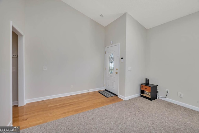 foyer featuring light carpet, light wood-type flooring, and baseboards