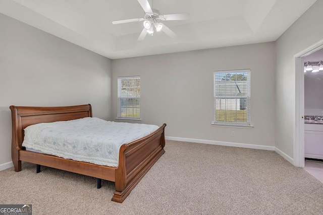 bedroom featuring a tray ceiling, multiple windows, carpet, and baseboards