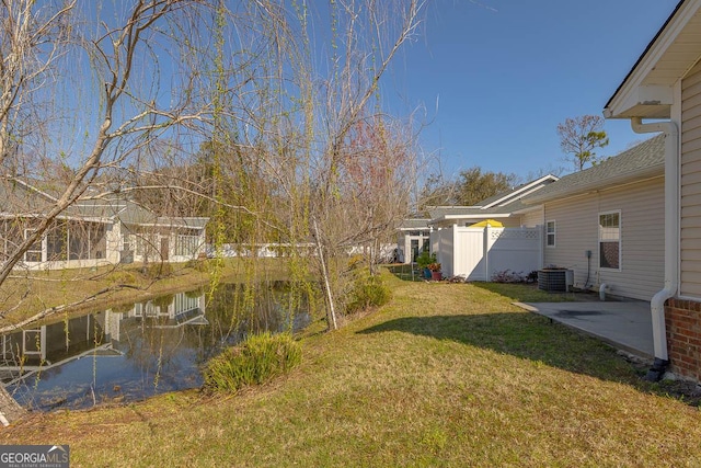 view of yard with central air condition unit, a patio, fence, and a water view