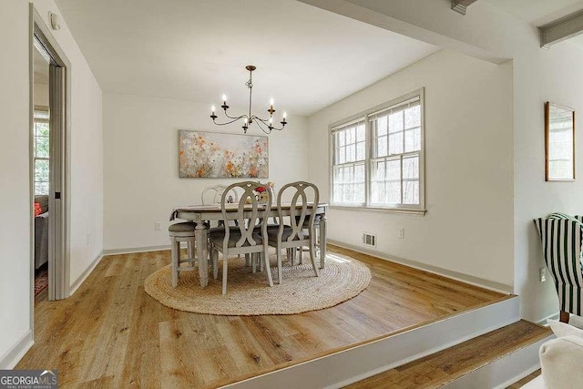 dining area with visible vents, wood finished floors, baseboards, and a chandelier