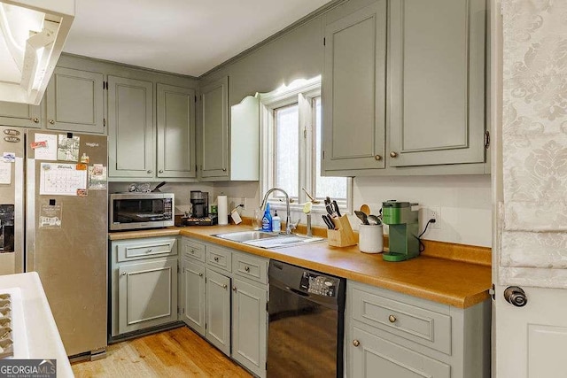 kitchen with a sink, light wood-style floors, appliances with stainless steel finishes, and light countertops