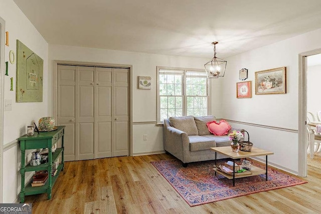 living area featuring light wood-type flooring, baseboards, and a notable chandelier