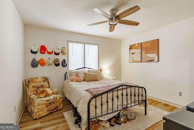 bedroom featuring baseboards, light wood-type flooring, and a ceiling fan