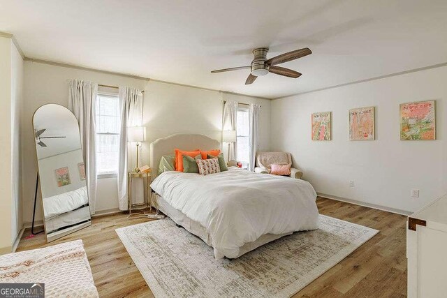 bedroom with ceiling fan, baseboards, light wood finished floors, and ornamental molding