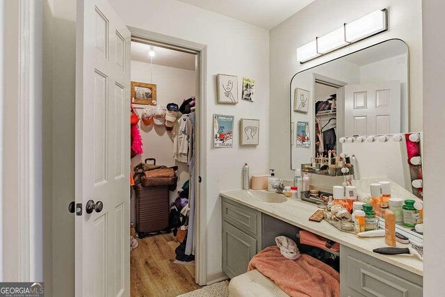 bathroom with a closet, vanity, and wood finished floors