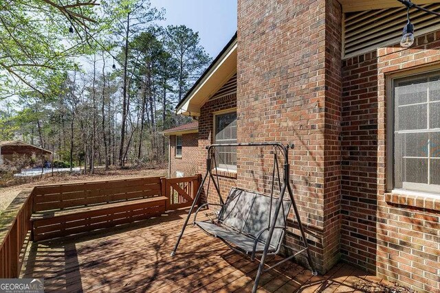 exterior space featuring brick siding and a wooden deck