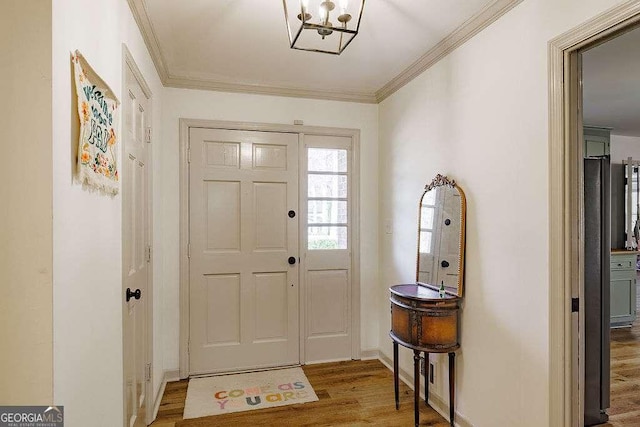 foyer entrance with crown molding, wood finished floors, and baseboards