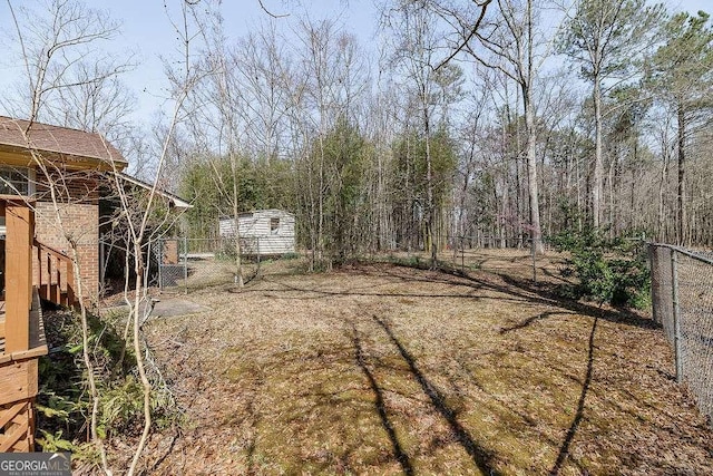 view of yard with an outbuilding, fence, and a shed