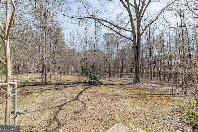 view of yard with a wooded view and fence