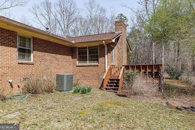 view of property exterior with cooling unit, brick siding, a deck, and a chimney