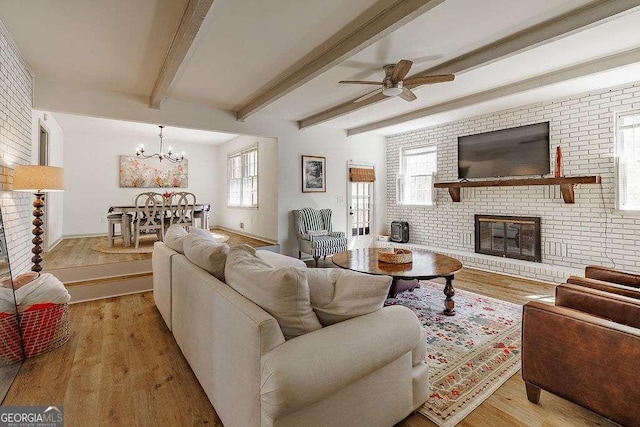 living area featuring beam ceiling, brick wall, a fireplace, and light wood finished floors