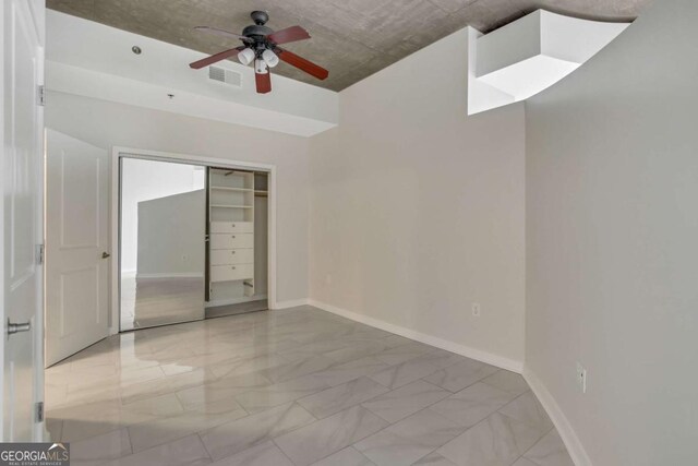 unfurnished bedroom featuring visible vents, marble finish floor, a closet, baseboards, and ceiling fan