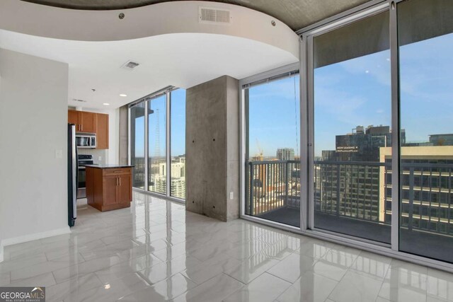 unfurnished room featuring visible vents, a city view, and expansive windows