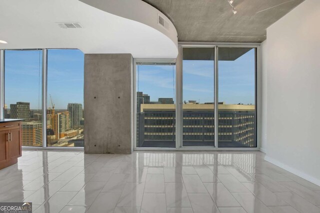 spare room featuring a wall of windows, visible vents, and a city view