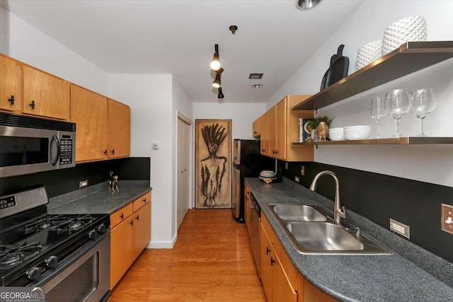 kitchen with open shelves, a sink, stainless steel appliances, light wood-style floors, and dark countertops