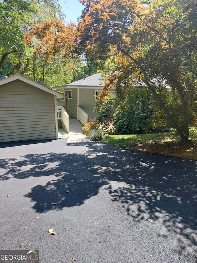 view of side of property featuring aphalt driveway and an outbuilding