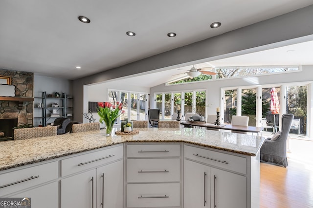 kitchen with lofted ceiling, white cabinets, a fireplace, and open floor plan