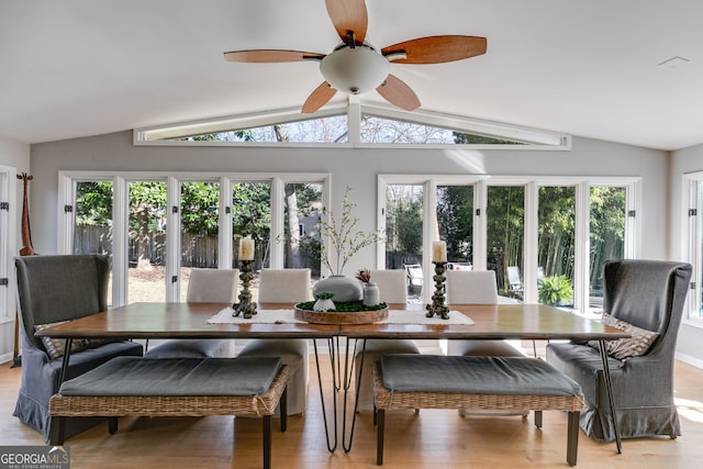 dining space featuring ceiling fan, vaulted ceiling, and light wood-style flooring