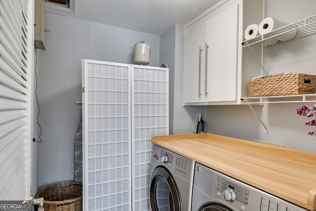 clothes washing area featuring cabinet space and washer and clothes dryer