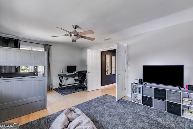 living area featuring baseboards, ceiling fan, visible vents, and wood finished floors