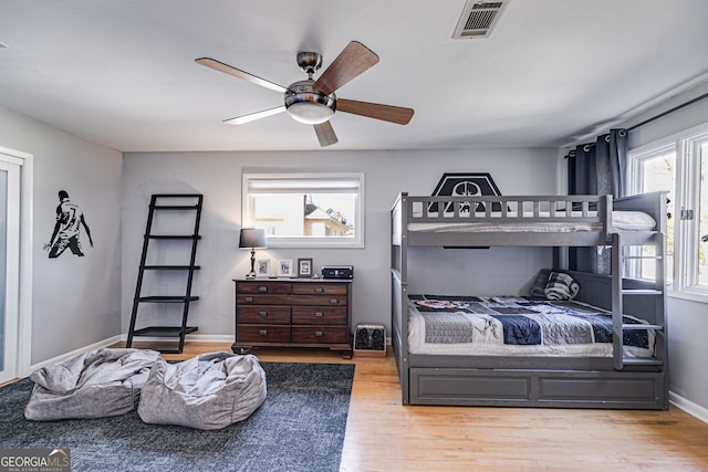 bedroom with visible vents, baseboards, wood finished floors, and a ceiling fan