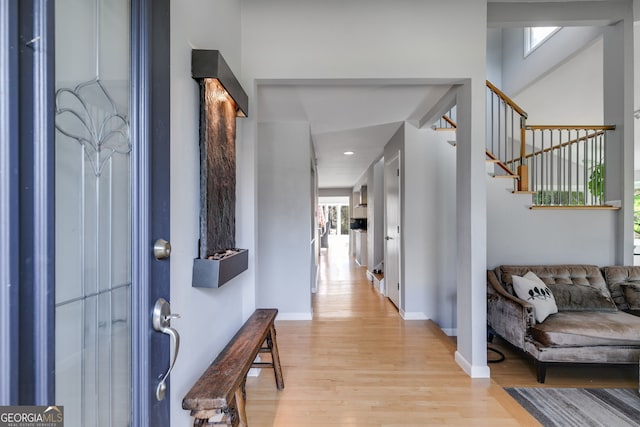 foyer featuring stairway, baseboards, and light wood finished floors