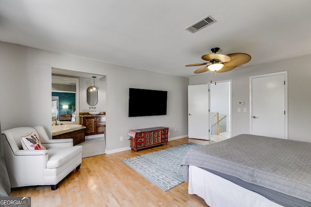 bedroom featuring ensuite bath, light wood-style floors, visible vents, and baseboards