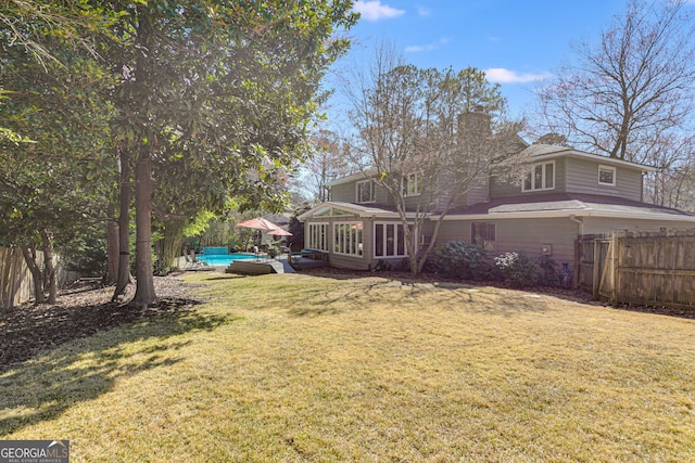 view of yard featuring fence, a fenced in pool, and a sunroom