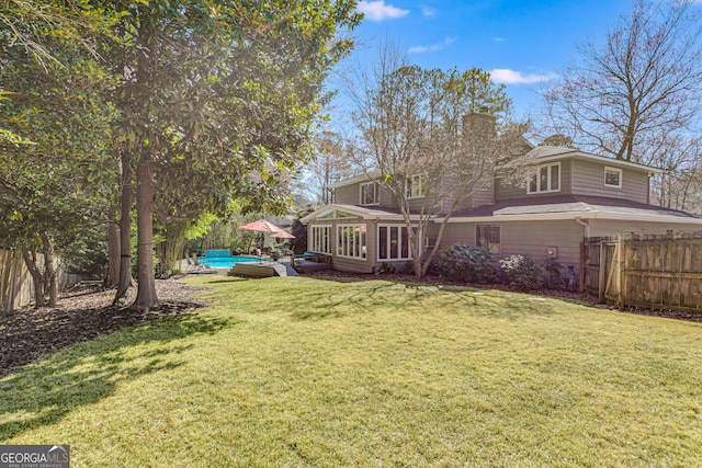 view of yard featuring a sunroom, a fenced backyard, a fenced in pool, and a deck
