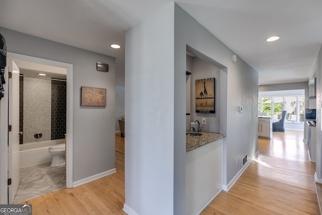 hall with recessed lighting, light wood-style flooring, baseboards, and visible vents
