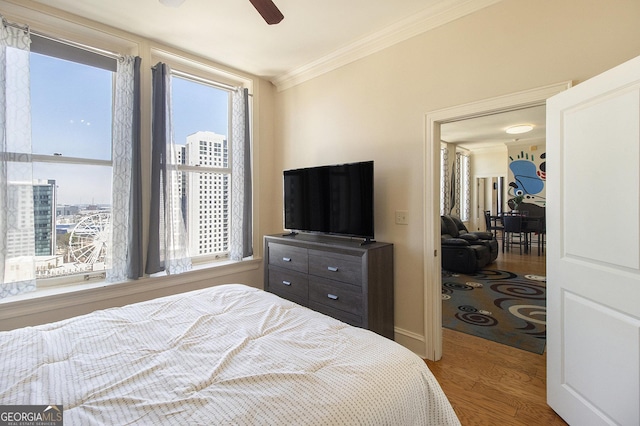 bedroom with ornamental molding, ceiling fan, and wood finished floors